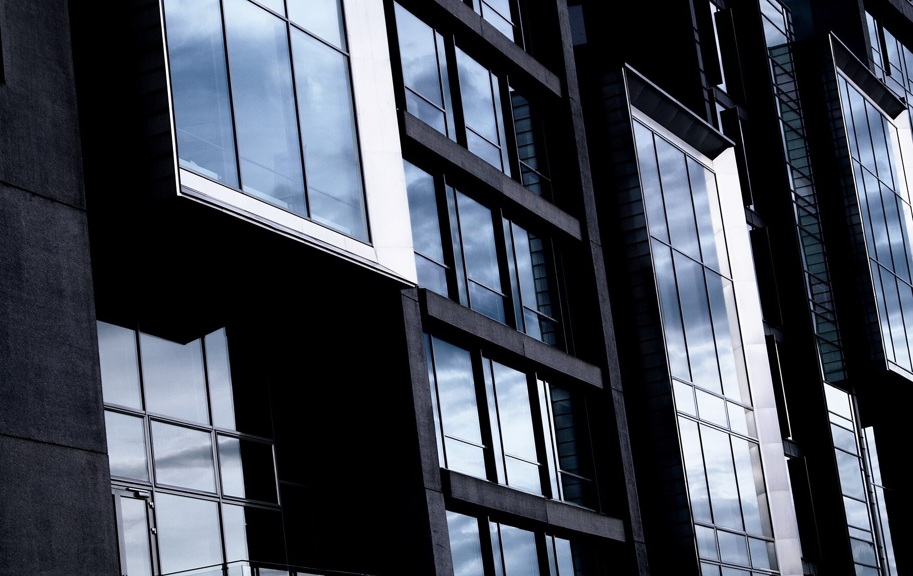Modern 'black and gray building' showing reflections of the cloudy syky in the windows of the facade by Matthias Heil, 2